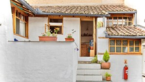 A building with a tiled roof, a small entrance with steps, and potted plants. - Studio Mariposa with a fantastic garden in the historical Quito (Quito)