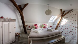 A bedroom with a bed, a wardrobe, a small stool, and a window with a view.