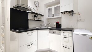 A modern kitchen with white cabinets, black countertops, a built-in oven, and a coffee machine. - 58m² classic apartment for 2-4 people in the center (Wien)