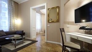 A modern living room with a sofa, glass coffee table, and a desk with a chair. A large mirror and flat-screen TV are mounted on the wall. - 58m² classic apartment for 2-4 people in the center (Wien)