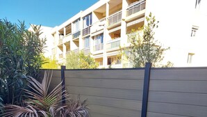 Uma área residencial com cerca de madeira, vasos de plantas e um caminho de brita.