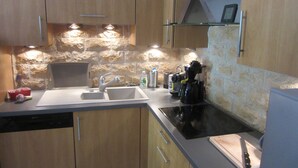 Uma cozinha moderna com armários de madeira, painel de backsplash de pedra, lava-louças embutida e máquina de café.