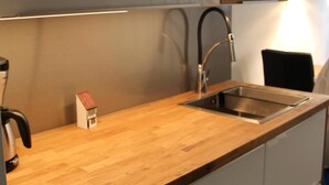 Una cocina moderna con encimera de madera, pileta de acero inoxidable y muebles de cocina blancos.