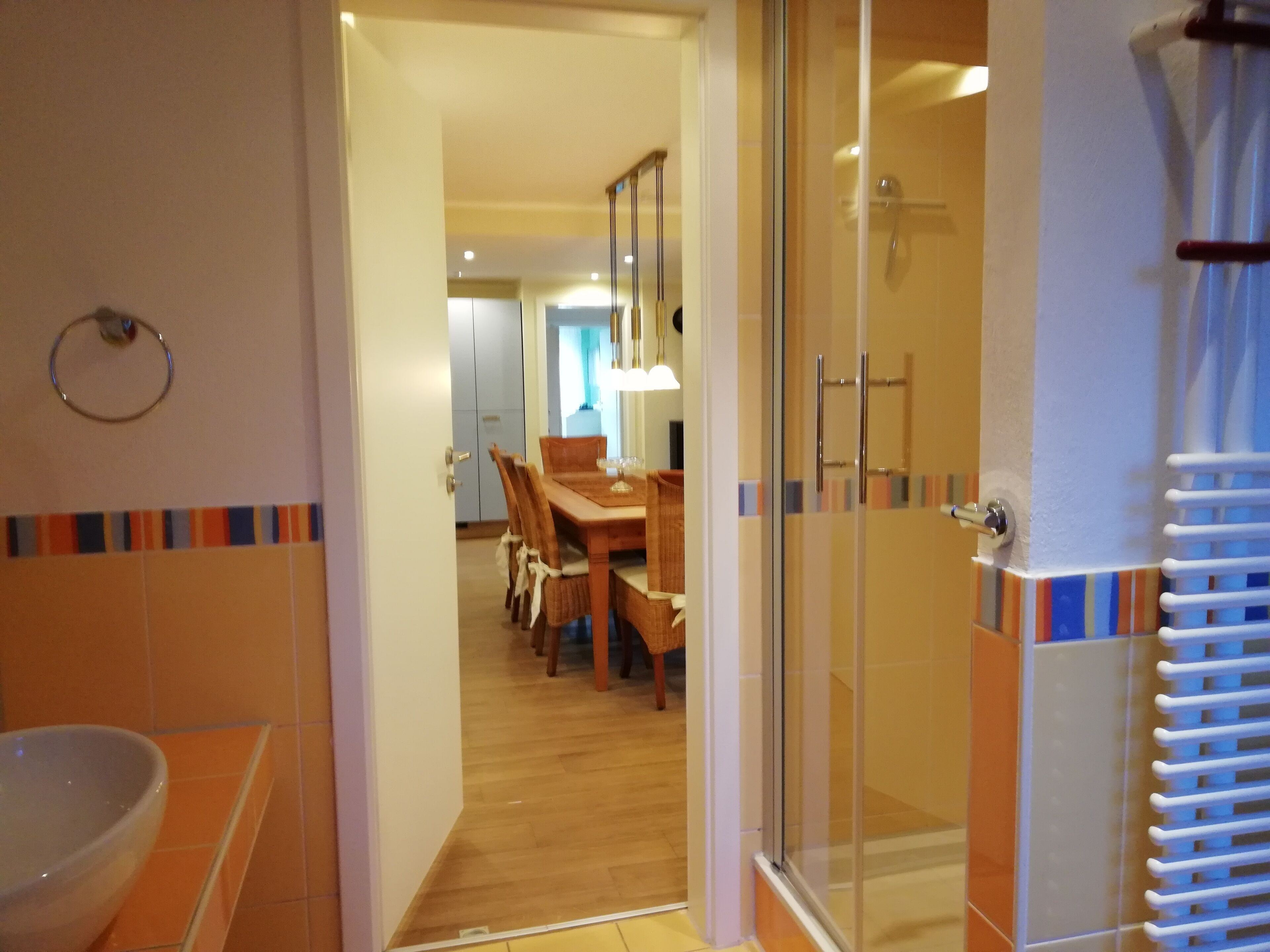 Een badkamer met een douchecabine van glas, een wastafel en een betegelde vloer.