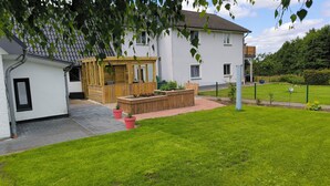 A house with a garden, a wooden deck, and a fenced yard.