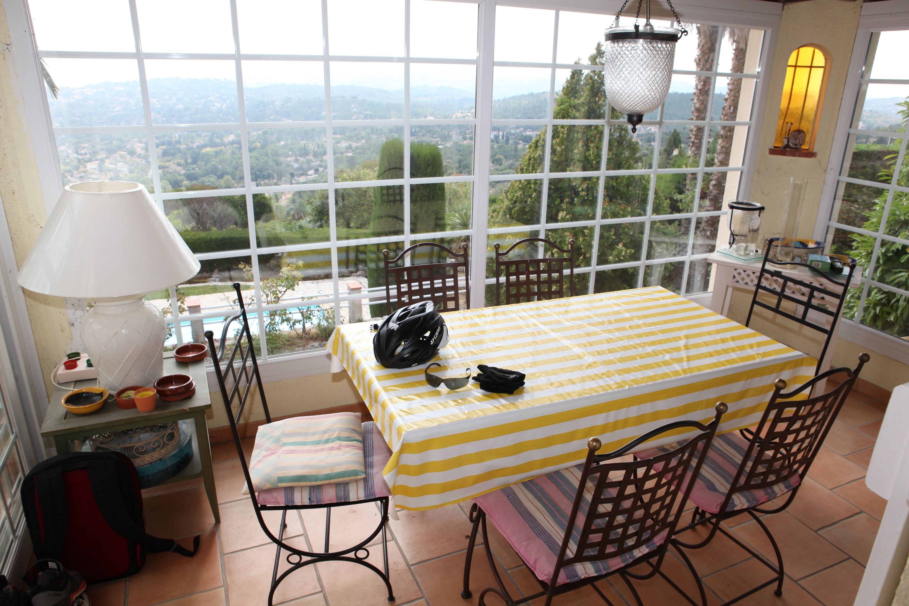 A room with a bed, a table with chairs, a lamp, and a view of the landscape.