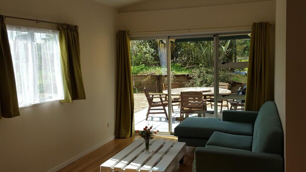 A living room with a sofa, a coffee table, and a sliding glass door leading to an outdoor patio with a table and chairs.