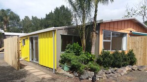 A single-story building with a yellow exterior and a wooden deck.