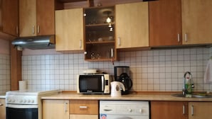 A kitchen with wooden cabinets, a microwave, a coffee maker, a washing machine, and a stove. - Exquisite apartment  (Sector 5)