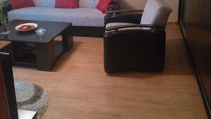 A living room with a grey sofa, red cushions, a black armchair, a coffee table, and a painting on the wall. - Exquisite apartment  (Sector 5)