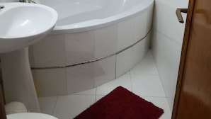 A bathroom with a white bathtub, a white sink, and a toilet. - Exquisite apartment  (Sector 5)