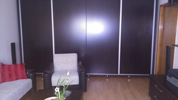 A living room with a sofa, a coffee table with a vase of flowers, and a TV stand. - Exquisite apartment  (Sector 5)