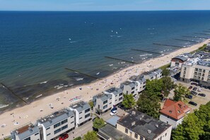 Ein Hotel an der Küste mit mehreren Gebäuden, einem Strand mit Sonnenschirmen und Meerblick.