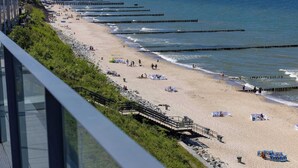 Ein Strand mit einer Promenade, Sonnenschirmen und Menschen.