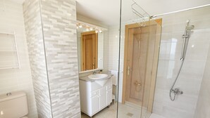 Een badkamer met toilet, wastafel, spiegel en douche.