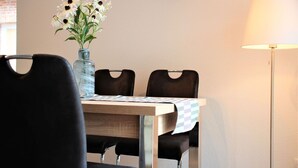 Ein Essbereich mit Tisch, Stühlen, einer Blumenvase, einer Wanduhr und einer Stehlampe.