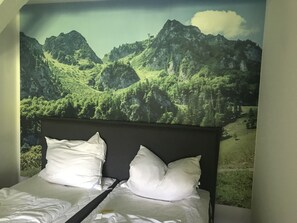Relax in a serene space with a large bed and a stunning mural of a mountainous landscape above.