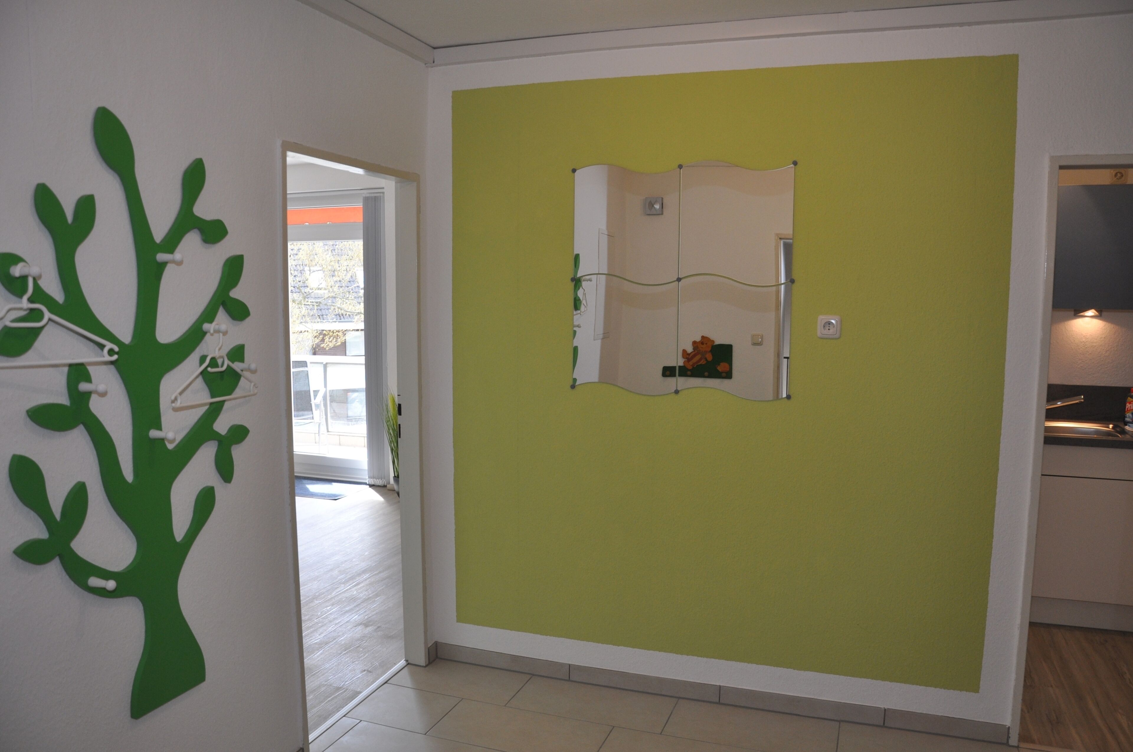 A room with a green wall, a white door, and a tree decoration.