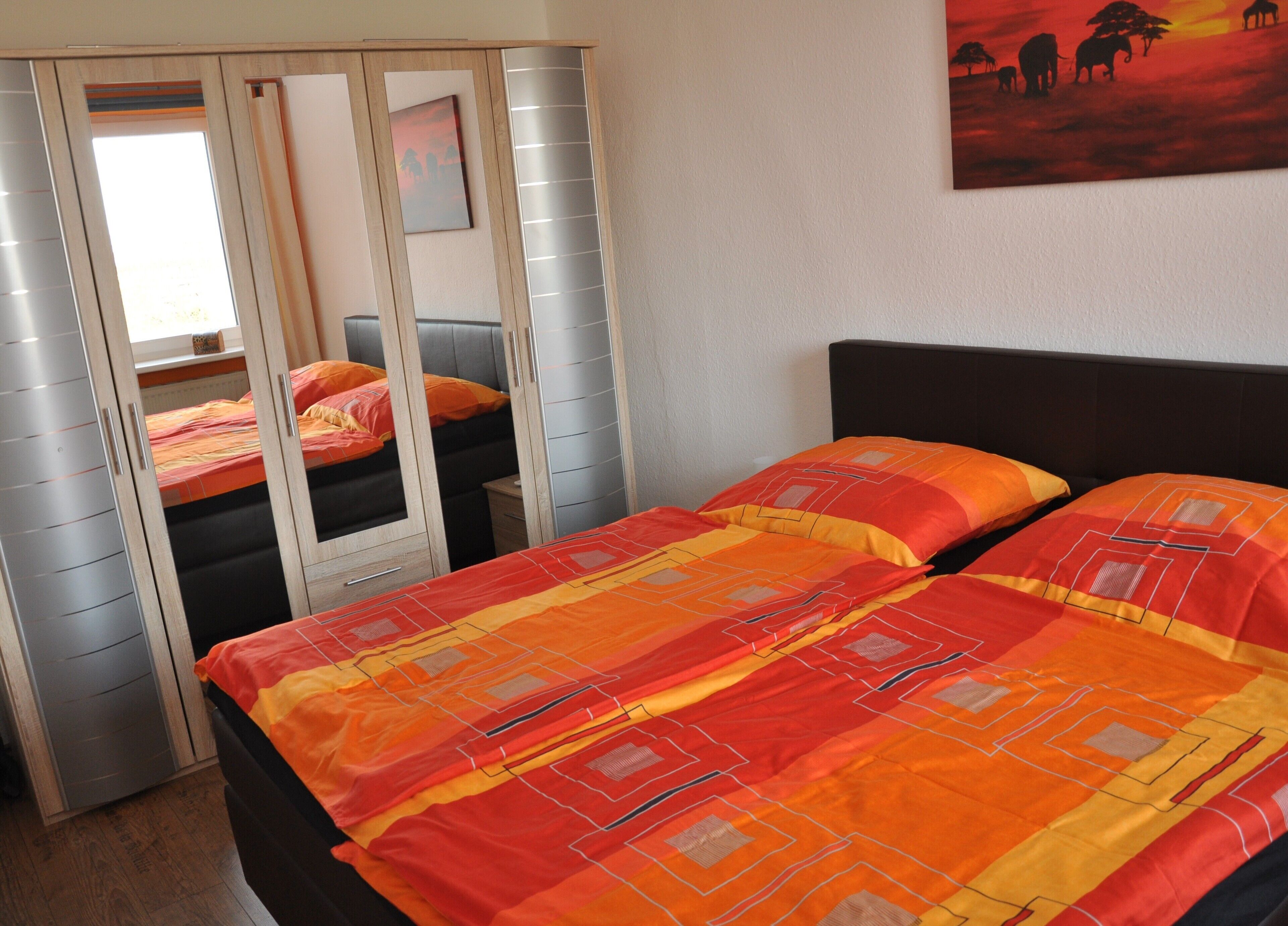 Un dormitorio con dos camas, un armario y un cuadro en la pared.