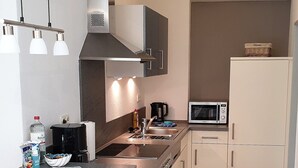 Una cocina moderna con una isla central, taburetes de bar, microondas y cafetera.