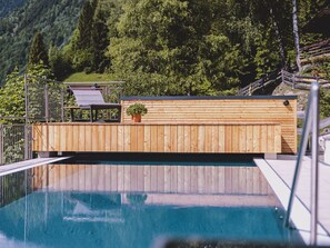 A wooden deck with a pool, surrounded by a metal railing and a wooden fence.