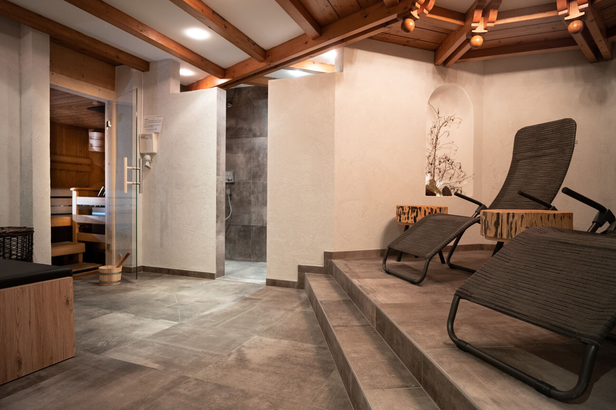 A spa area with a wooden bench, a small wooden table, and a glass shower enclosure.