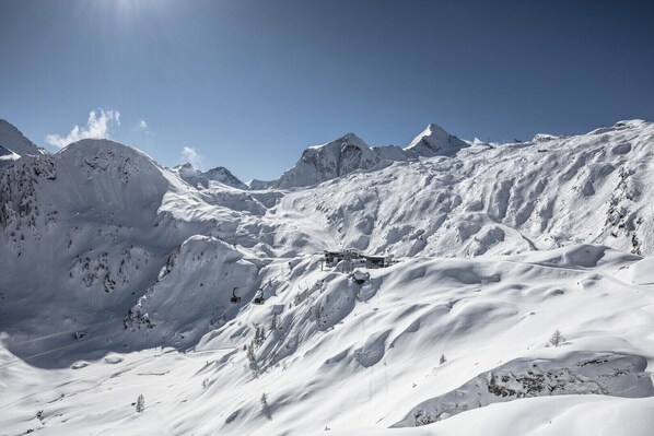 A snow-covered mountain landscape with a ski lift and a building.