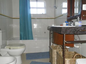 Een badkamer met toilet, bad en wastafel met spiegel.
