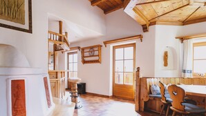 A rustic kitchen with wooden beams, a dining area with a bench, and a large window.