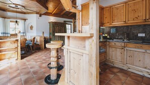 A rustic kitchen with wooden cabinets, a stone countertop, and a unique wooden stool.