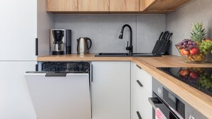 A modern kitchen with a Bosch dishwasher, a coffee maker, a kettle, and a fruit bowl on the counter.
