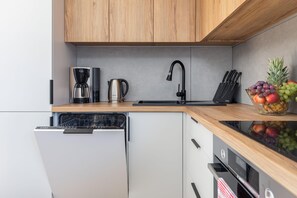 Eine moderne Küche mit einem Geschirrspüler von Bosch, einer Kaffeemaschine, einem Wasserkocher und einer Obstschale auf der Arbeitsfläche.