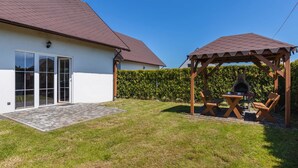 A house with a patio, a wooden pergola, and a barbecue area.