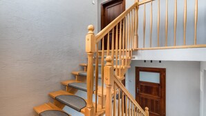 A wooden staircase with a handrail, grey carpeted steps, and a door at the bottom.