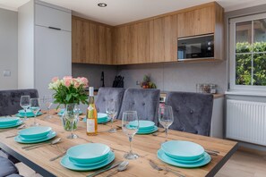 Eine moderne Küche mit grau gepolsterten Stühlen, einem Holzkasten und einem eingebauten Backofen.