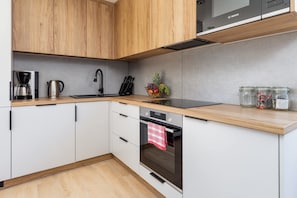 Une cuisine moderne avec des meubles en bois, une machine à café Bosch en acier inoxydable, un évier et un four encastré.