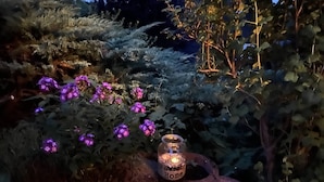 Un jardín con flores púrpuras y un candelabro que dice 'Home Sweet Home'.