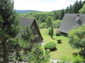 A house with a sloped roof surrounded by a well-maintained lawn and dense forest. - Directly at the Bleilochtalsperre - pure nature experience - Finnhütte Karli Saaldorf (Bad Lobenstein)