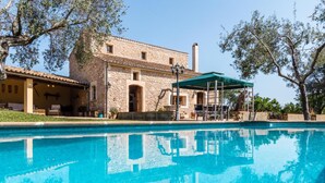 Un edificio in pietra con una piscina di fronte.