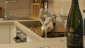 Una encimera de cocina con una botella de champán, dos copas y una hogaza de pan.