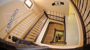 Una escalera de caracol con barandilla de madera y una pared con un letrero que dice "ZARAGOZA".