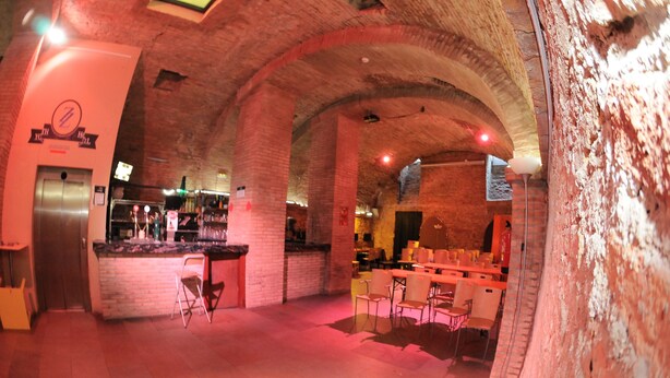 Un restaurante con arcos de ladrillo, una zona de bar y asientos.