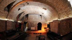Un interior de ladrillo con arco que presenta un escenario, una zona de asientos y una chimenea.