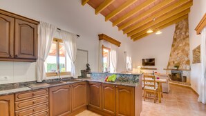 A spacious kitchen with wooden cabinets, a marble countertop, and a stone fireplace. - Rural finca with pool Can Grau Petit in Mallorca (Sencelles)
