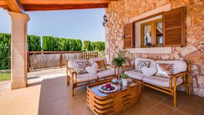 A covered outdoor seating area with wicker furniture and a stone wall backdrop. - Rural finca with pool Can Grau Petit in Mallorca (Sencelles)