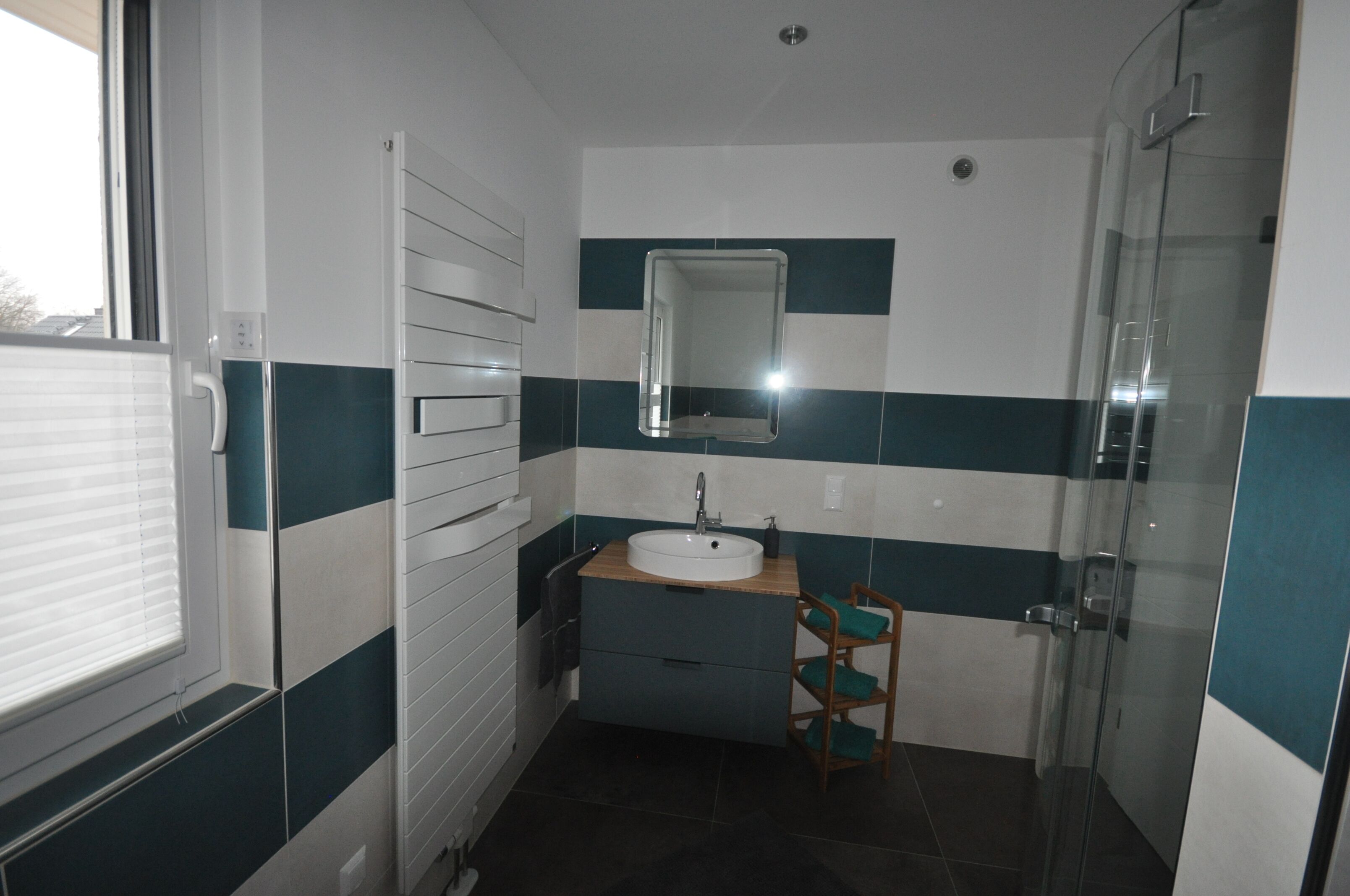 Un baño con lavamanos, espejo y cabina de ducha de vidrio.