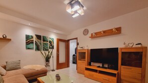 Ein modernes Wohnzimmer mit einer Couch, einem Couchtisch, einer TV-Konsole und Kunstwerken an den Wänden.