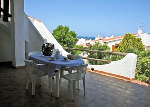 A balcony with a table set for two, chairs, and a view of the sea and buildings. - Holiday home on the sea in Sardinia - satellite TV, washing machine and sea view (Valledoria)