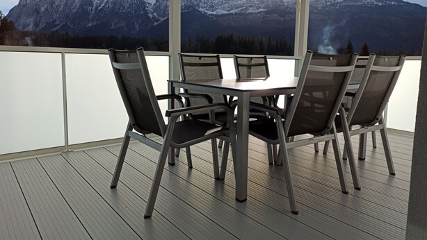 A covered outdoor dining area with a table and chairs, overlooking a mountainous landscape. - Apartment avalanche stone (Bad Mitterndorf)