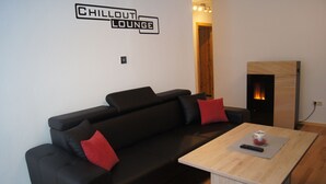 A modern living room with a black sofa, red cushions, a wooden coffee table, and a fireplace. - Apartment avalanche stone (Bad Mitterndorf)